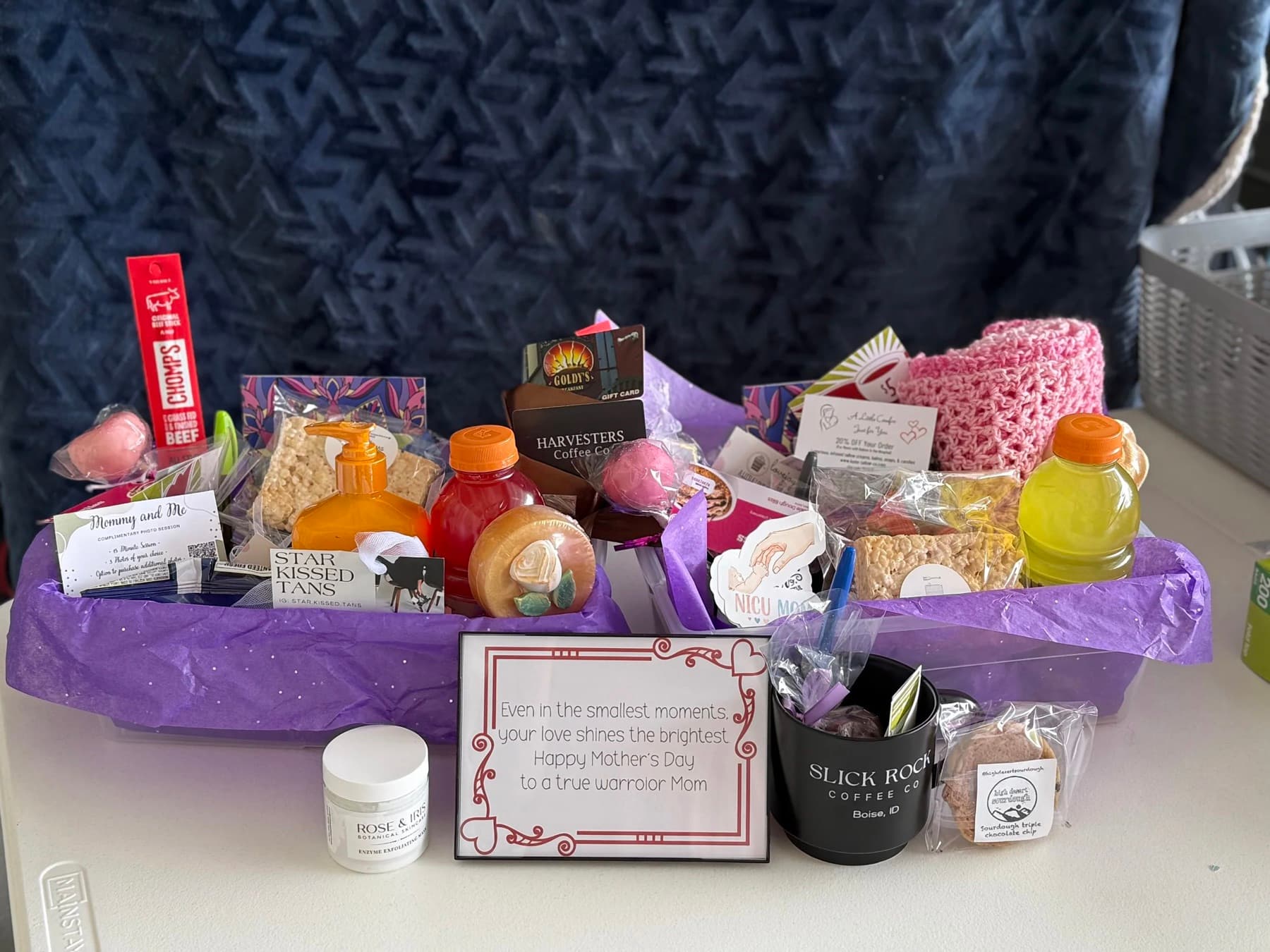A finished NICU care basket with snacks, drinks, a coffee mug, lotion, gift cards, and a note reading “Happy Mother’s Day to a true warrior Mom”
