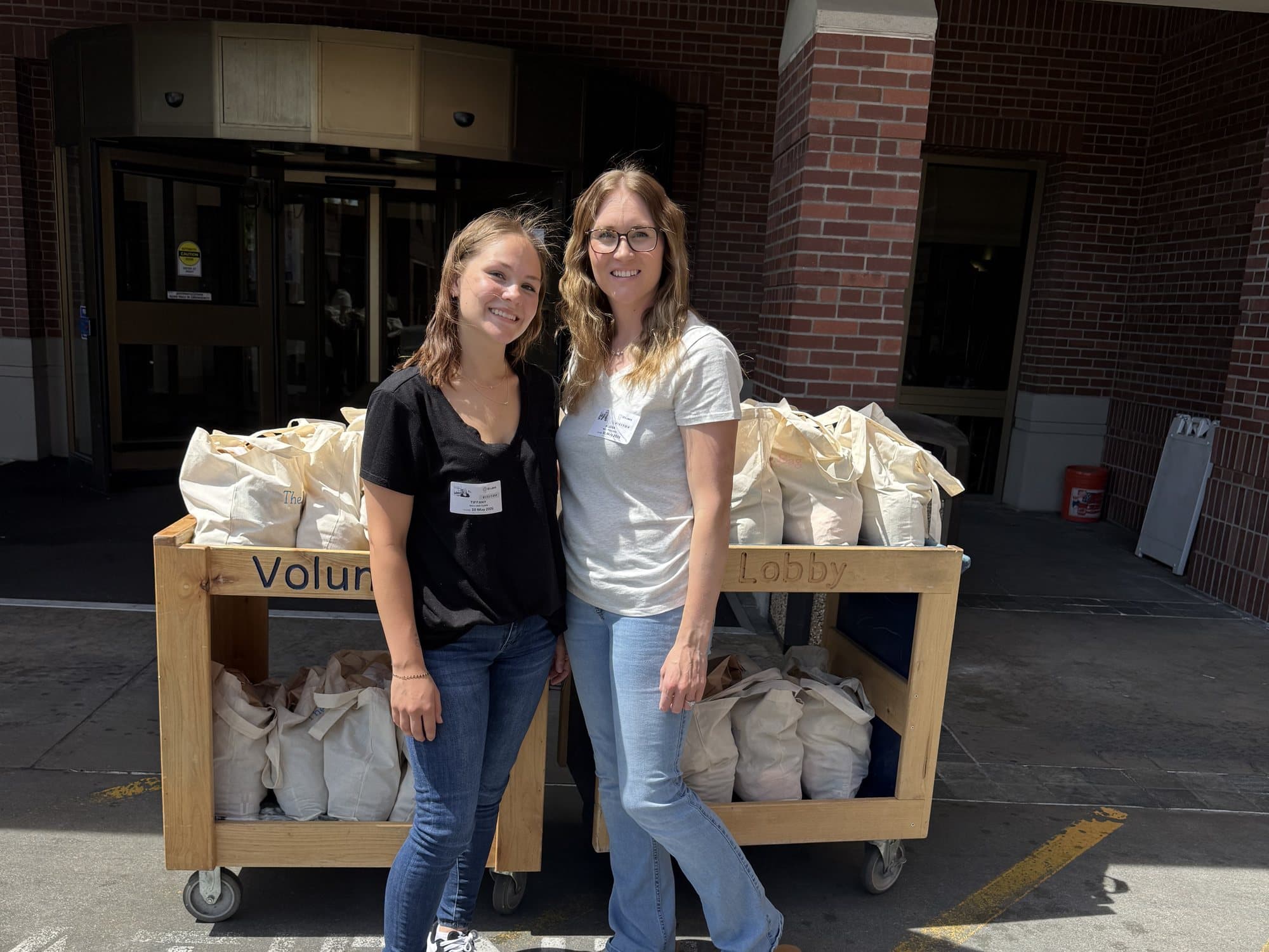 Tiffany and Alyssa with carts of 2026 delivery bags outside the hospital