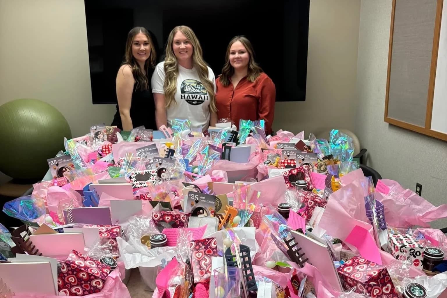 Volunteers standing behind a table full of Mother’s Day care baskets for NICU moms